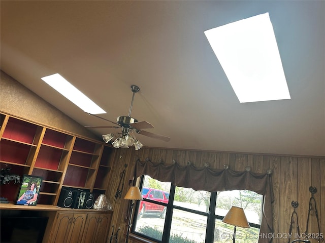 details with a ceiling fan, a skylight, and wood walls