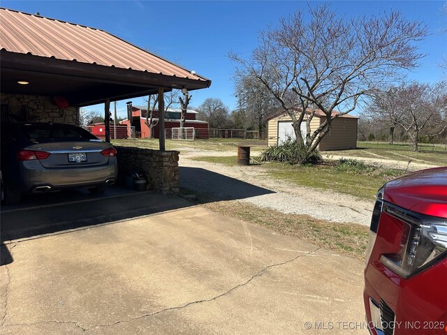 exterior space with driveway, fence, an outdoor structure, and an attached carport