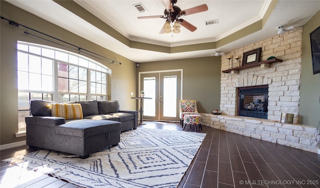 living room featuring visible vents, wood finished floors, ceiling fan, and a raised ceiling