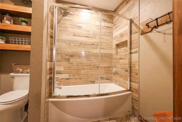 full bathroom featuring a textured wall, toilet, and enclosed tub / shower combo