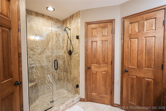 bathroom with a stall shower, baseboards, and marble finish floor