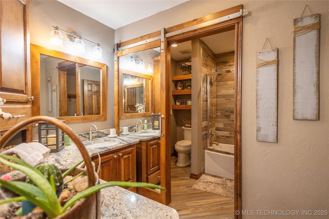 full bathroom with double vanity, a sink, toilet, and wood finished floors