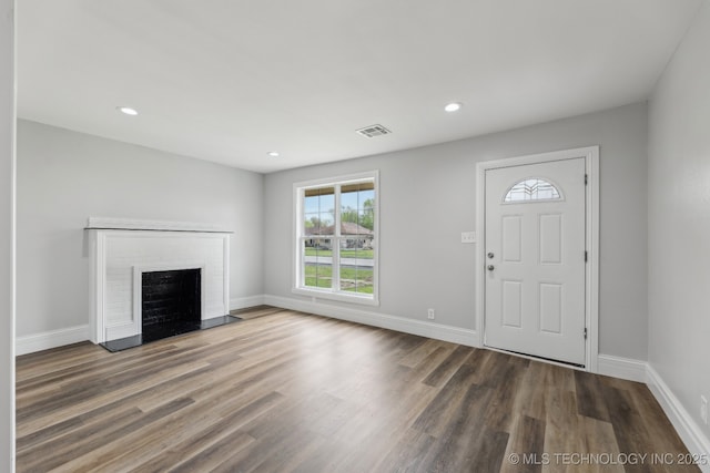 719 S 7th St, Muskogee, OK 74401 - entrance foyer with a brick fireplace, wood finished floors, and recessed lighting