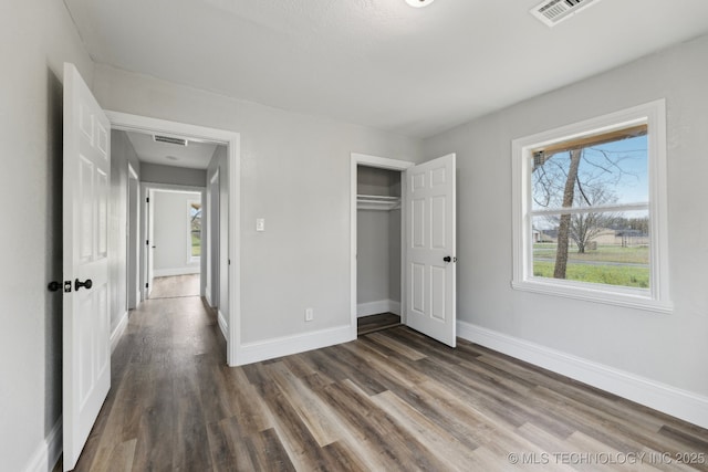 719 S 7th St, Muskogee, OK 74401 - unfurnished bedroom featuring dark wood finished floors, multiple windows, and a closet