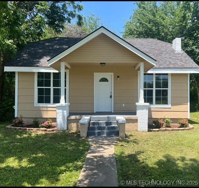719 S 7th St, Muskogee, OK 74401 - bungalow-style home featuring a front yard, a chimney, and a shingled roof