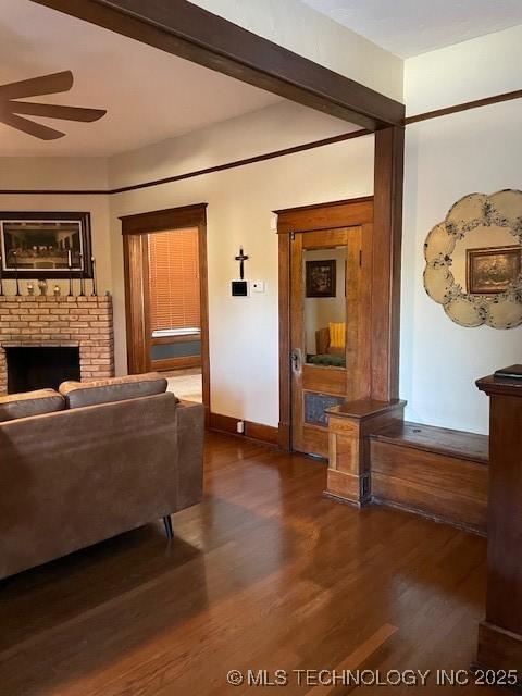 living area featuring a ceiling fan, dark wood-style flooring, a fireplace, and baseboards