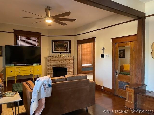 living area featuring ceiling fan, wood finished floors, a fireplace, and baseboards