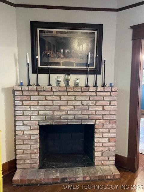 detailed view of ornamental molding, wood finished floors, baseboards, and a brick fireplace