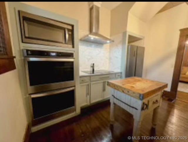 121 F SW, Ardmore, OK 73401 - kitchen featuring wall chimney exhaust hood, butcher block countertops, dark wood-style floors, a sink, and lofted ceiling