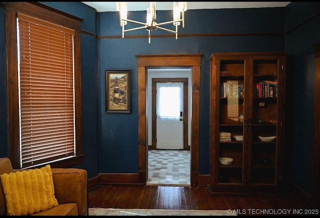 doorway with a chandelier, baseboards, and wood finished floors