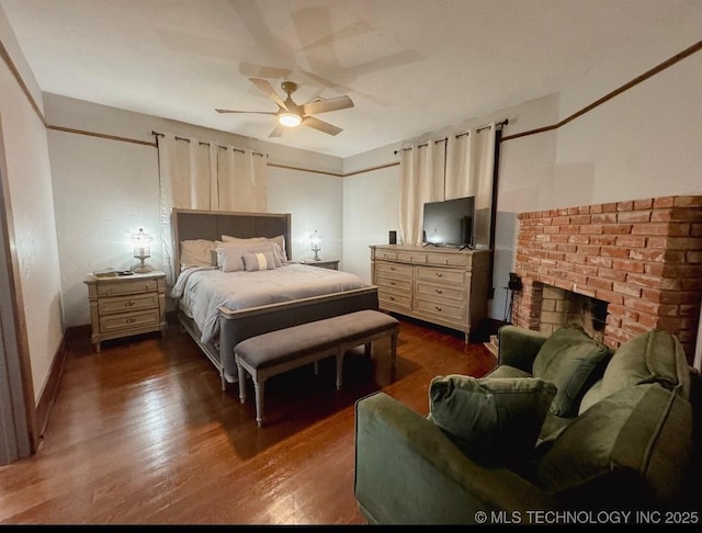 bedroom with dark wood-style floors, a brick fireplace, baseboards, and a ceiling fan