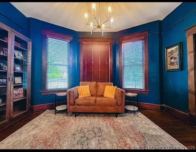 living area featuring baseboards, a chandelier, wood finished floors, and healthy amount of natural light