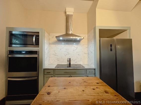 kitchen featuring stainless steel appliances, butcher block counters, wall chimney range hood, and backsplash