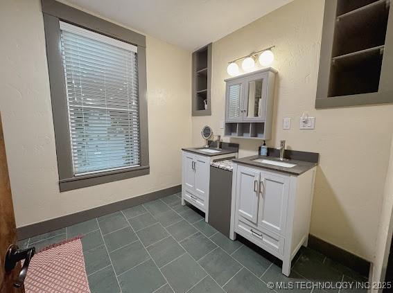 bathroom featuring two vanities, baseboards, built in shelves, and tile patterned flooring