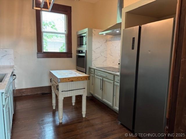 121 F SW, Ardmore, OK 73401 - kitchen featuring stainless steel appliances, tasteful backsplash, dark wood-style floors, light countertops, and wall chimney range hood