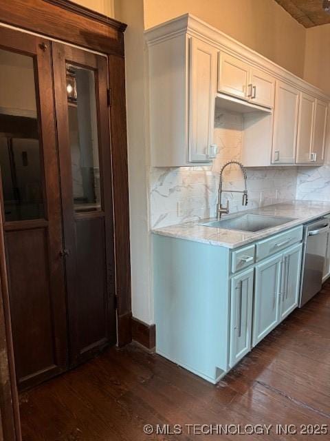 121 F SW, Ardmore, OK 73401 - kitchen featuring a sink, dark wood-style floors, stainless steel dishwasher, decorative backsplash, and light stone countertops
