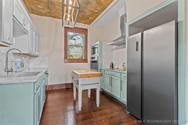 121 F SW, Ardmore, OK 73401 - kitchen featuring stainless steel appliances, wall chimney range hood, dark wood-style flooring, tasteful backsplash, and light countertops