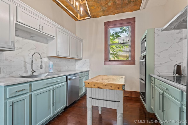 121 F SW, Ardmore, OK 73401 - kitchen featuring appliances with stainless steel finishes, decorative backsplash, dark wood-style flooring, range hood, and white cabinetry
