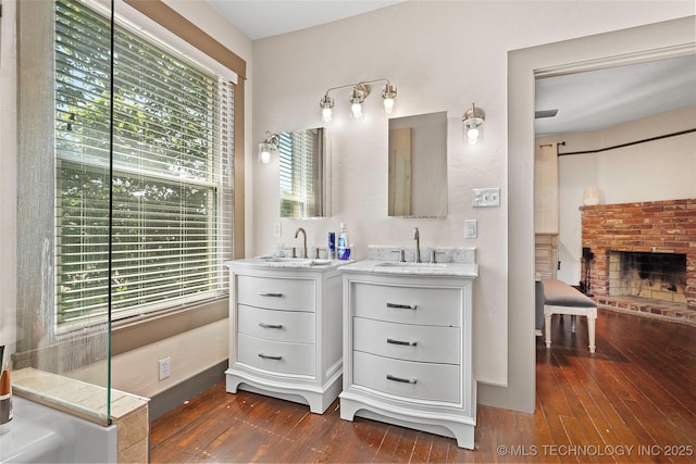 121 F SW, Ardmore, OK 73401 - bathroom featuring two vanities, hardwood / wood-style floors, and a brick fireplace