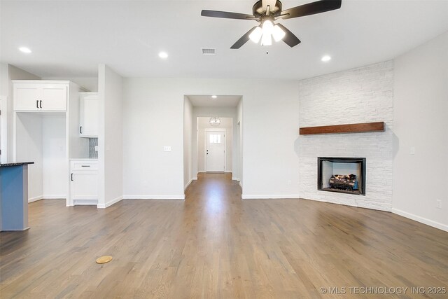 23192 E 106th St S, Broken Arrow, OK 74014 - unfurnished living room with visible vents, baseboards, ceiling fan, a fireplace, and wood finished floors