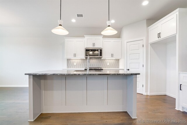 23192 E 106th St S, Broken Arrow, OK 74014 - kitchen with visible vents, stainless steel microwave, dark stone counters, white cabinetry, and backsplash