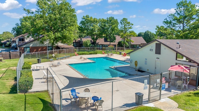 community pool featuring a lawn, fence, and a patio area
