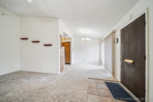 carpeted empty room featuring a notable chandelier, lofted ceiling, and a textured ceiling