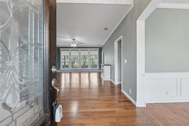 corridor with ornamental molding, wood-type flooring, and visible vents