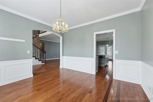 unfurnished dining area with wood-type flooring, arched walkways, stairs, and ornamental molding