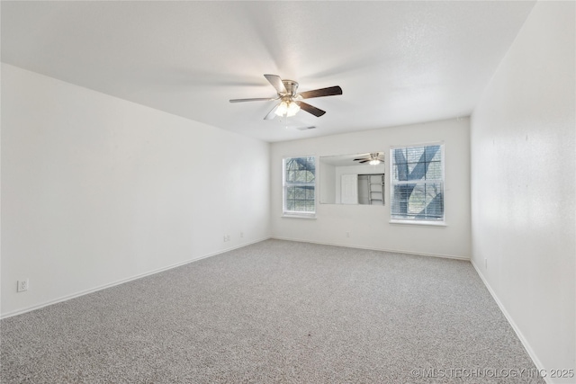 carpeted spare room featuring baseboards, a ceiling fan, and visible vents