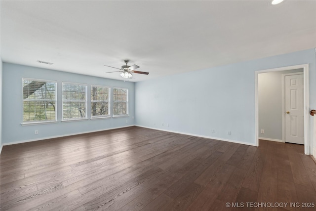 spare room with baseboards, ceiling fan, dark wood finished floors, and visible vents