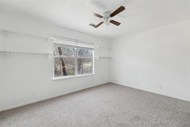 empty room with carpet floors, a ceiling fan, baseboards, and visible vents