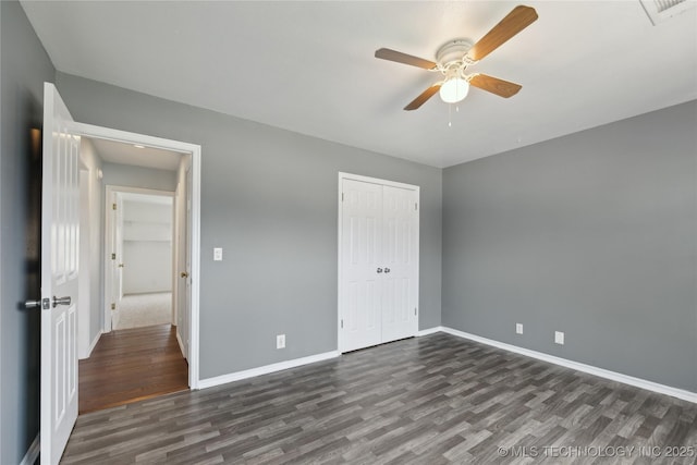 unfurnished bedroom with dark wood-type flooring, baseboards, and a closet
