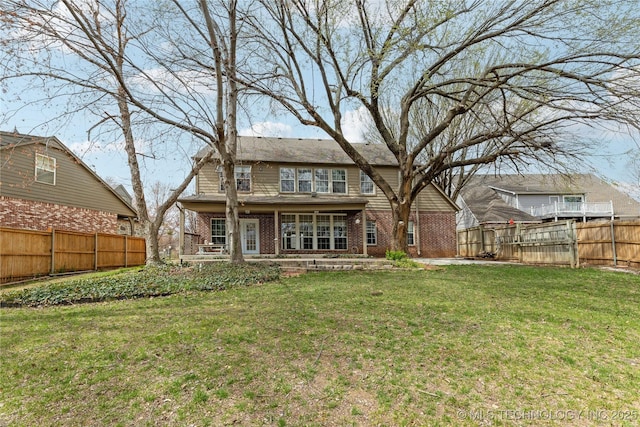 back of house with a lawn, a fenced backyard, and brick siding