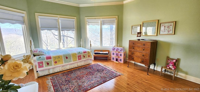 bedroom with multiple windows, wood finished floors, baseboards, and ornamental molding