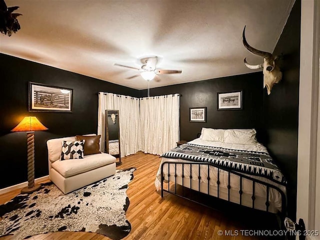 bedroom with a ceiling fan, baseboards, and wood finished floors