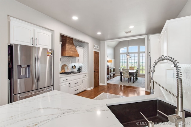 kitchen with visible vents, recessed lighting, custom range hood, a sink, and stainless steel appliances