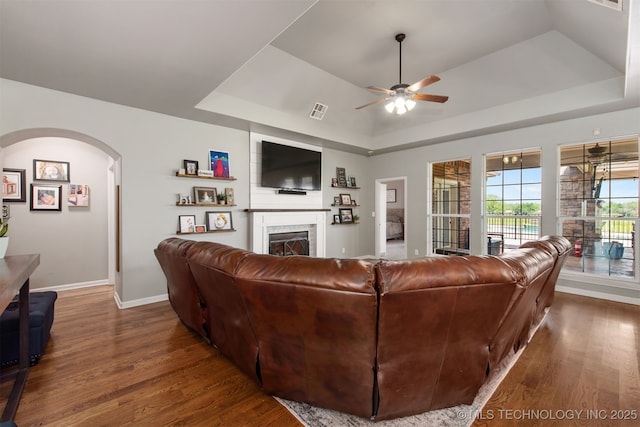 living room with a ceiling fan, wood finished floors, and a raised ceiling