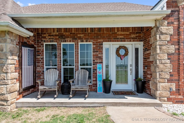 property entrance with brick siding and a shingled roof