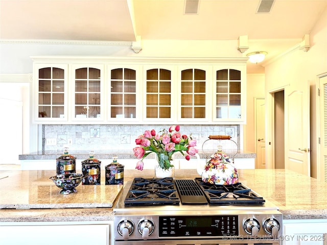 8315 N 99th E Ave, Owasso, OK 74055 - kitchen featuring gas stove, decorative backsplash, glass insert cabinets, light stone countertops, and white cabinetry