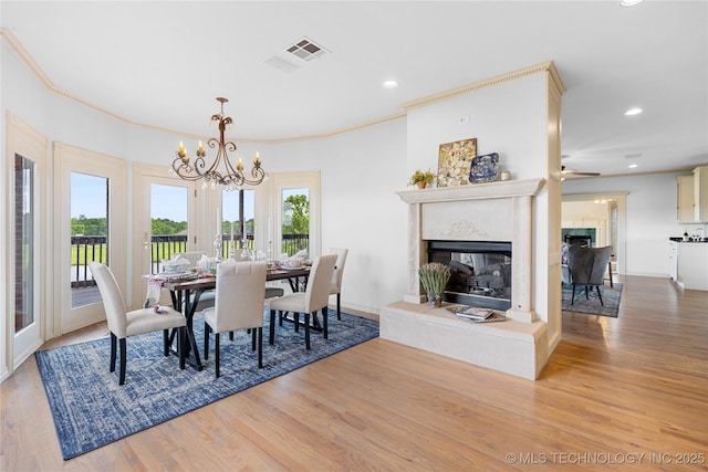 8315 N 99th E Ave, Owasso, OK 74055 - dining room with a multi sided fireplace, wood finished floors, a chandelier, crown molding, and recessed lighting