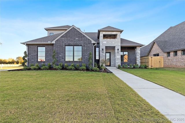 view of front of house with a front yard, fence, and brick siding