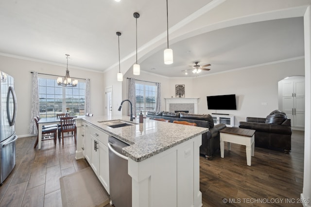 kitchen featuring dark wood-style floors, a sink, stainless steel appliances, a fireplace, and ceiling fan with notable chandelier
