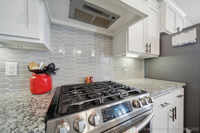 kitchen featuring range hood, decorative backsplash, light stone counters, gas stove, and white cabinets