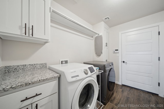 laundry area with visible vents, separate washer and dryer, cabinet space, and dark wood finished floors