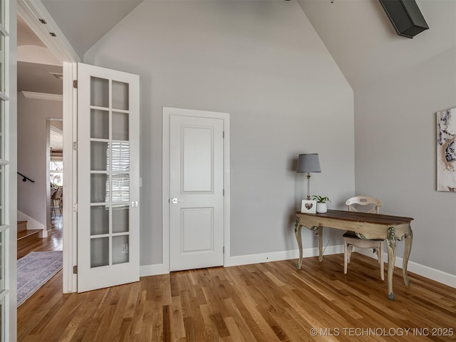 office space featuring baseboards, high vaulted ceiling, and wood finished floors