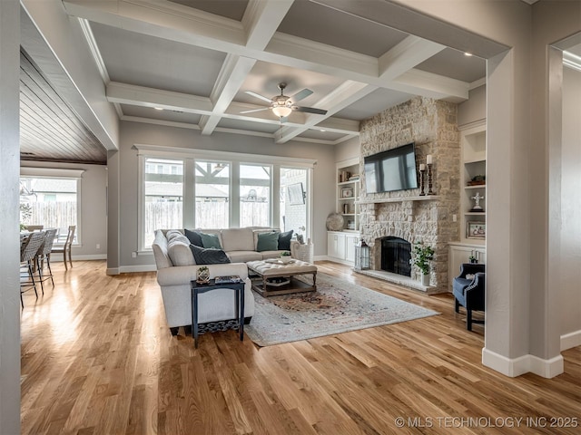 living room with baseboards, ceiling fan, light wood-type flooring, and a stone fireplace