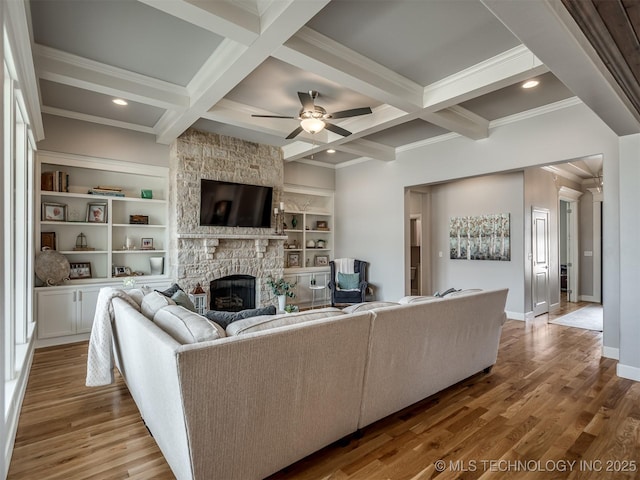 living room featuring beamed ceiling, a fireplace, and wood finished floors