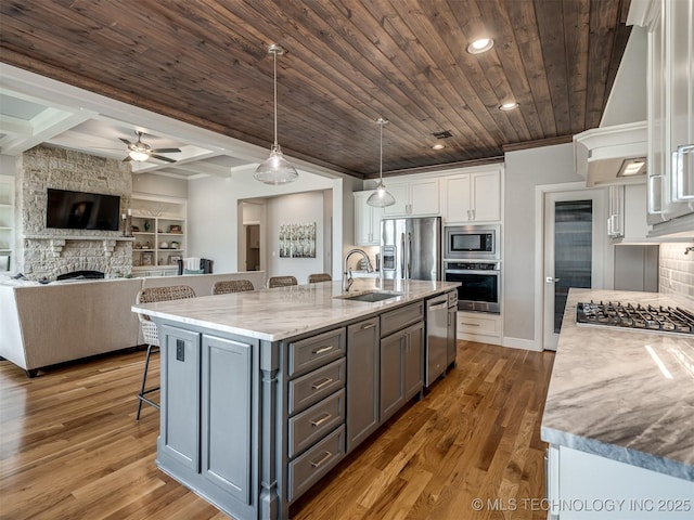 kitchen featuring white cabinetry, a kitchen bar, stainless steel appliances, a sink, and wood ceiling