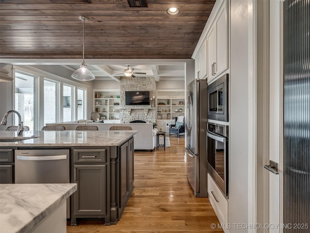 kitchen featuring a sink, a ceiling fan, appliances with stainless steel finishes, a stone fireplace, and open floor plan